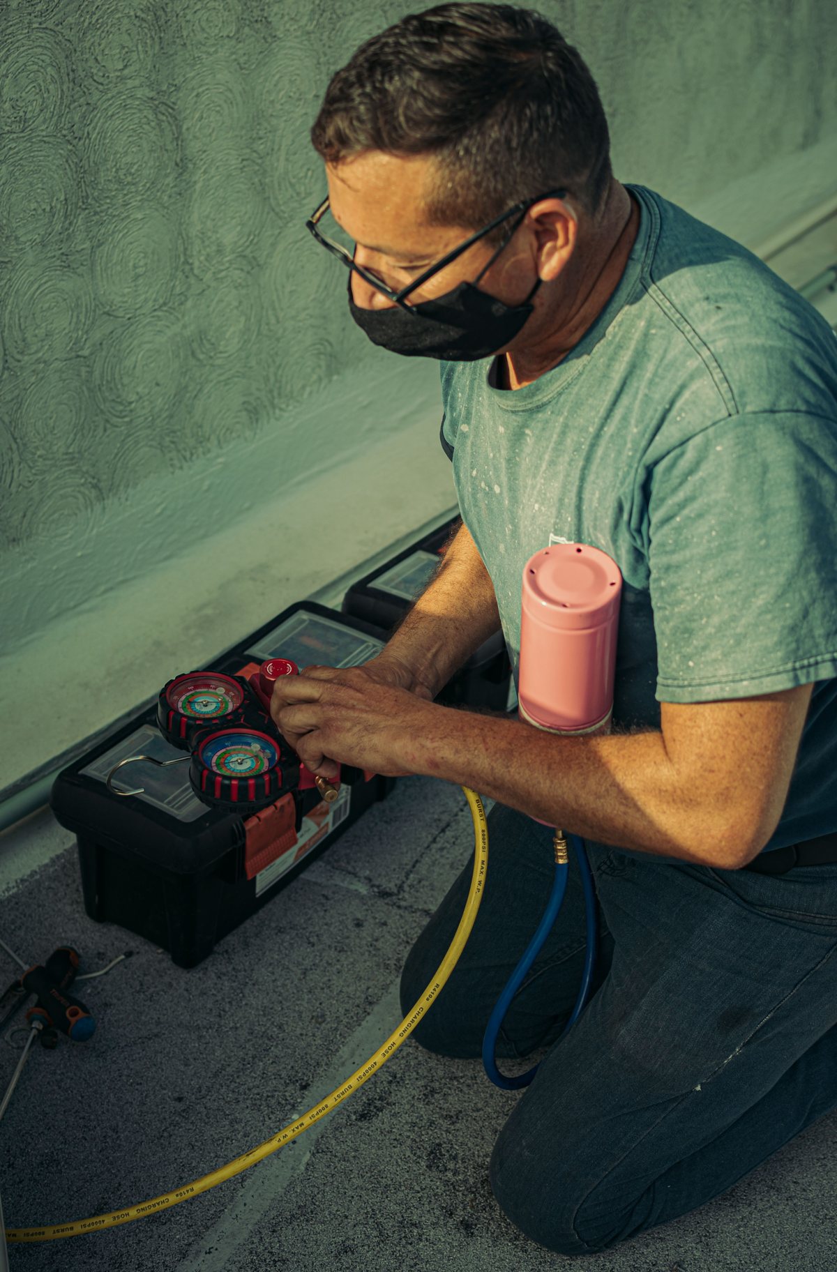 Stock photo of a technician using gauges while servicing HVAC equipment